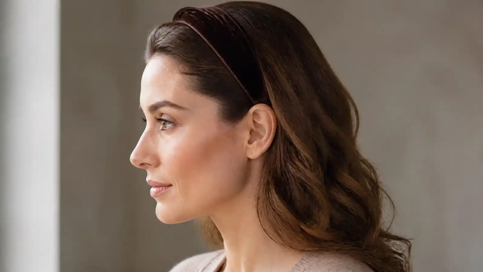 A velvet headband seated at the hairline in profile, with the end tucked neatly behind the ear